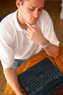 Our editors offer five helpful tips to help you learn how to write an essay. A young man is sitting in front of his laptop, stroking his chin in a thoughtful manner. He is wondering how to write an essay.