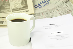 Our editors explain how to write a resume. A photo with a cup of coffee, a resume, and the newspaper open to the classified section.