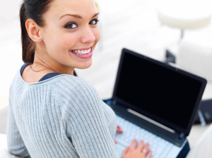 Our editors explain when you should use active and passive voice. A student smiles while working on her computer. She is writing an essay in the active voice.