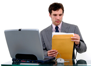 Our editors explain how to format a cover letter. An employer is sitting at a desk with a laptop in front of him. He is holding a manila envelope and reviewing a nicely formatted cover letter.
