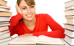 A young woman in a red sweater is sitting at a desk with Chicago Manual of Style Bibliography books around here.