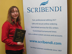 Scribendi.com President, Chandra Clarke, is standing next to a Scribendi.com sign holding an OWIT award plaque.
