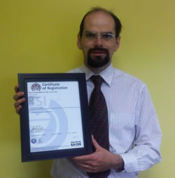 Vice-President, Terence Johnson, stands with Scribendi.com's ISO certificate. Scribendi.com Vice-President, Terence Johnson, standing with ISO certificate.