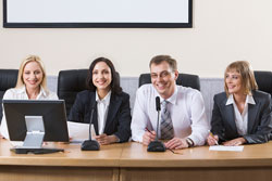 Four members of a thesis committee sit behind a table with microphones and a computer.