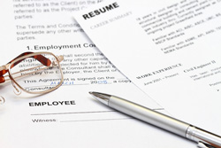 Our editors provides chronological resume examples. A chronological resume and an employment contract sit on a desk. A pair of glasses and a pen are on top of the papers.