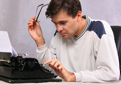 Our editors provide an example of a synopsis. A man sitting infront of a typewriter, holding his glasses in one hand and typing with the other.