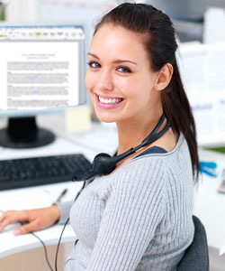 Our editors explain how to write short stories. A woman is sitting at a desk facing forward; a computer with an article about writing short stories is on the desk.