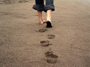 A photo of a person wandering in the sand, leaving footprints behind.