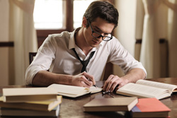 A man is sitting at his desk writing scripts for the stage.