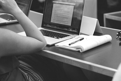 A person sits in front of a computer, looking at the screen.