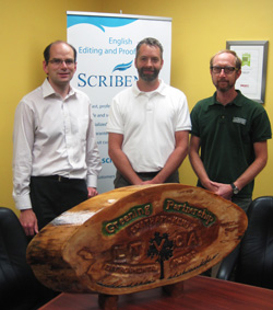 Vice-President Terry Johnson stands with Randall Van Wagner and Greg Van Every in the Scribendi.com boardroom with an award.