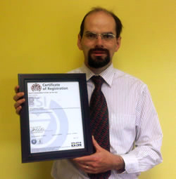Scribendi.com Vice-President, Terence Johnson, standing with ISO certificate.