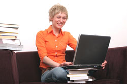 A female student is sitting on a red couch putting her studen't work through a word count tool to make sure they didn't go over the word count limit. 