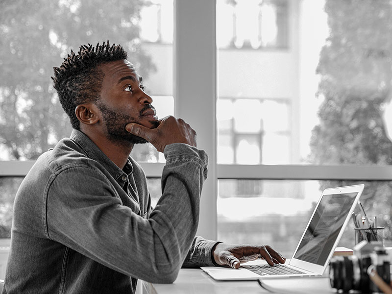 A pondering man working at his laptop.